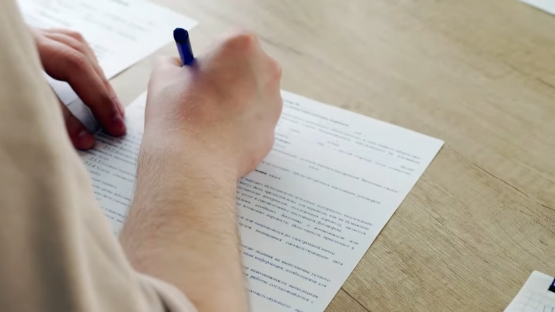 A Person Filling out Paperwork, Possibly for A Portugal Student Visa Application